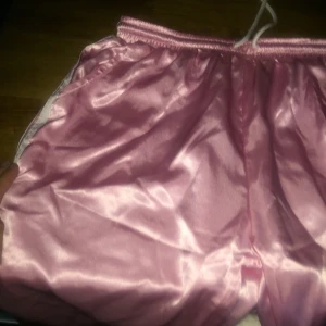 SKITsnygga ”Adidas” byxor - Obs ej adidas! Köpa i Tokyo. SKIT snygga och babryrosa. Skrynkliga på bilden pga jag haft dem nerpackade (bara att stryka) Silke/satin. Ser ut som riktiga adidas. Ingen lapp men ca 38. ALDRIG ANVÄNDA 💕💕