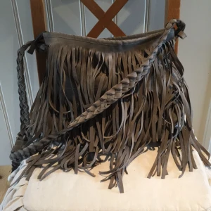  - Snygg mockaväska med fransar. Använt skick. Över ena innerfickan har sömmarna släppt, men går lätt att sy. Frakt tillkommer.