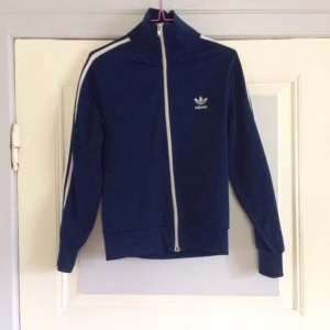  - 🔹Om du inte redan har en: här är chansen! Klassisk Adidas zip i blått & vita ränder. Storlek okänd, passar mig som är XS-S (Bild2). Från Adidas, lapparna borta. Troligtvis polyester. Välanvänd av mig i yngre år, gott begagnat skick. Frakt: 39kr. 🔹