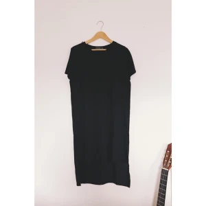  - Svart klänning i fint material. Längre tyg över rumpan och kortare framtill. Fint skick!