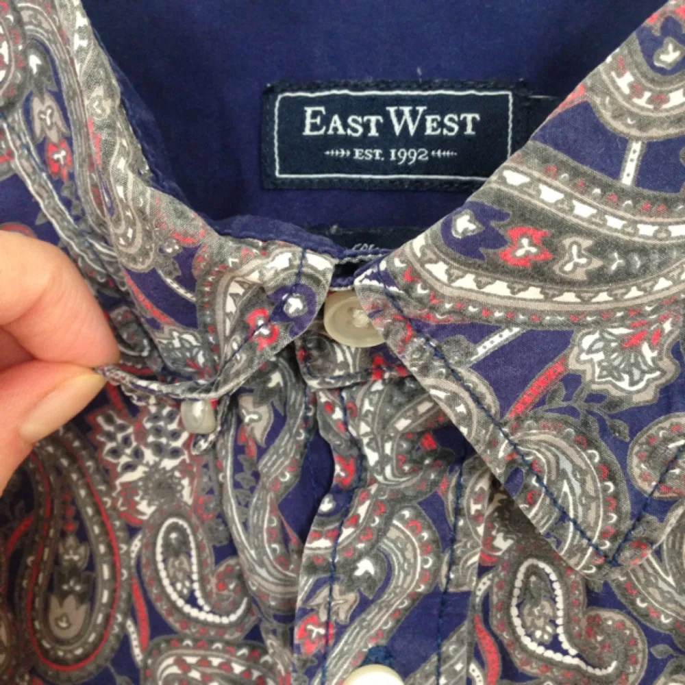 Skjorta från East West i fint paisleymönster och i nyskick.   Storlek L. Dold button down.. Skjortor.