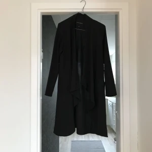  - Svart omlottkofta som även kan användas som klänning med bälte/snöre. Tunt svalt tyg, ej genomskinligt!  Jättesnygg på 🖤