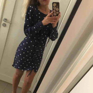  - Blå vit prickig klänning med små axelvaddar och dragkedja där bak. Det finns knytning så att man själv kan reglera hur den ska sitta. Swish. Köparen står för frakt 