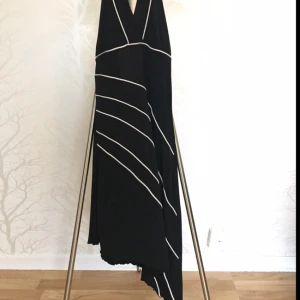  - Svart klänning med vita ränder och ojämnt slut vid knäna. Superskön och elastisk så passar de flesta kroppsformer. Endast använd ett fåtal gånger.   Tar endast swish eller kontant. 