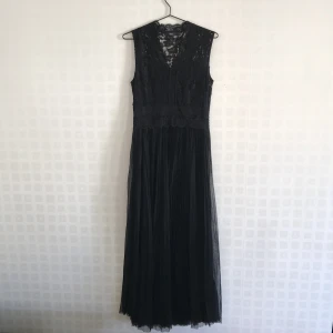 Svart tuff balklänning - Om du ska på bal eller fin fest men inte vill gå 100 procent prinsessa är den här klänningen perfekt! Den övre delen av klänningen är i spets och den undre i plisserad tyll. Klänningen är till fötterna på mig utan skor och jag är 168 cm lång. 