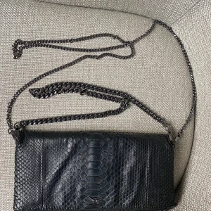 Zadig & Voltaire väska svart pyton  - Knappt använd och i bra skick, i pyton skin och inte som de resterande väskorna de säljer och därav priset. Nypris ca 7000. Medföljer två band, ett långt och ett kort.