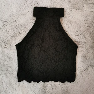 Crop top  - Crop top i spets från Gina Tricot. Ärmlös och med cut out på ryggen, samt knappar i bak för att knäppa kragen. Längst ned är det endast spets och inget innertyg. Använd ett fåtal gånger. Storlek S.