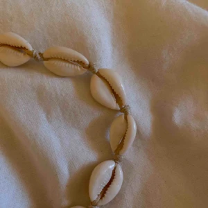  - Superfint snäckhalsband med vita och en guldig snäcka. Köpt i somras men har bara används ca 2 gånger. Hör av dig vid ev frågor eller fler bilder! 