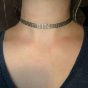  - Choker halsband i metall. Den kan som längst bli 39 cm och som kortast 29 cm. Köparen betalar frakten