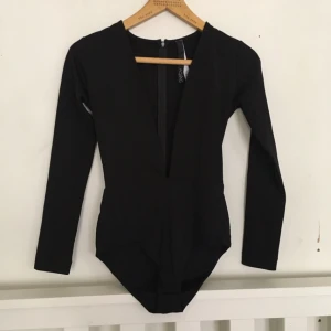  - Svart djupt v-ringad body från ASOS. Aldrig använd. 