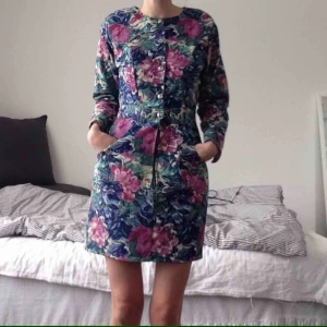  - Vintageklänning i jeansmaterial från märket Bee Berlin (made in California). Pastellfärgat blommönster med silverknappar och dragkedja där fram. Skön 80-tals känsla.   Stl S. Använd en gång.   Bekväm, smickrande och one of a kind! 