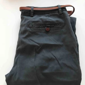  - Grå chinos med tillhörande brunt skärp som går att ta bort. Använda men i gott skick. Frakt tillkommer 😊