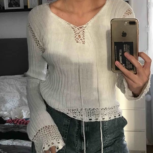  - Vit finstickad tröja med långa utsvängda ärmar och snörning upptill. 