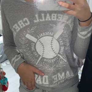 Grå tröja - En fin långärmad tröja från Gina Tricot, den har ett vit tryck på bröstet och har väldigt skönt tyg. Är i storlek XS men passar även större storlekar.