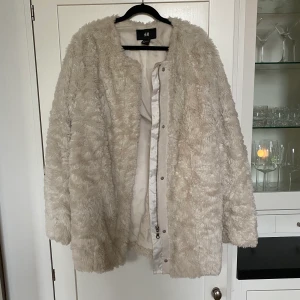 Vit kappa i fuskpäls från H&M - Vit kappa i fuskpäls från H&M. Använd endast ett fåtal gånger så i mycket bra skick! Supermysig för vintern🥰 