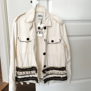 Jacka från Zara, prislapp kvar. - Vit/beige jacka från Zara med detaljer nertill. Aldrig använd och prislappen sitter kvar. Nypris är 450kr, säljer för 190kr. Kan mötas upp i Örebro/Eskilstuna/Arboga, annars står köparen för frakt. 