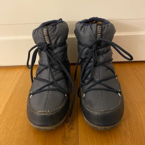 Moon boots låga blåa - Ett par låga moon boots i marin blå. Köpte förra vinter och är använda till viss del. Strl 40. Köpte dom för 1500kr och säljer för 400, buda i kommentarerna eller kontakta mig privat för intresse! (Fläcken på den högra skon är bara vatten då jag tvättade dom)