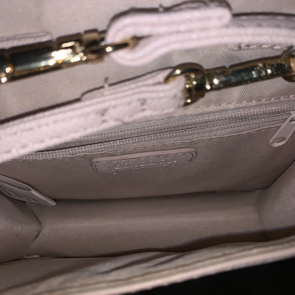 En rosa liten väska med två olika band, en guldkedja och ett rosa i samma material som väskan. Accessoarer.