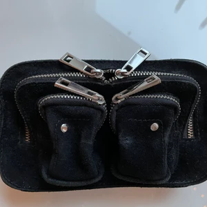 Nunoo väska - Svart liten väska från nunoo. Mycket använd men fortfarande i okej skick. Ett längre mocca band och en kedja medföljer. Nypris: 1099kr.