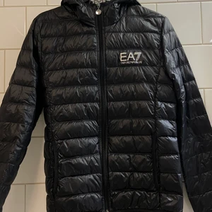 Ea7 dunjacka - EA7 jacka i storlek S. Knappast använd men det finns ett jack på insidan av jackan ungefär vid EA7 lappen som syns på den andra bilden. Orginalpris 1600 kr. Frakt ingår ej i priset 