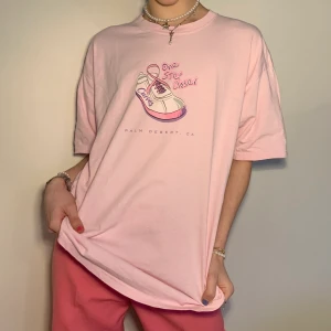 Oversized rosa grafic tee med sneaker tryck - Sååå mysig oversized rosa graphic tee/t-shirt från Palm Desert CA med ett rosa och lila sneaker tryck + texten ”One Step Closer” I den ballaste fonten 🌸 Så snygg till ett par vanliga/neutrala byxor och med matchande vita, rosa eller lila accessoarer!    Alla priser är inkl. frakt och alla plagg tvättas innan de skickas iväg