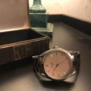  - Silverfärgad klocka från regal. Reglerbar storlek.  Batteri måste bytas. Frakt tillkommer