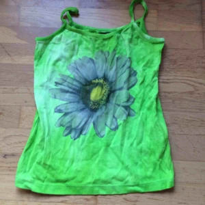  - Neongrönt batiklinne med en blomma framtill. Märkt M men litet i storlek så mer en XS-S. Frakt: 42 kr i postens påse 