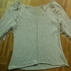  - Stickad tröja med fransar från Nelly. Urringning baktill. 40kr.