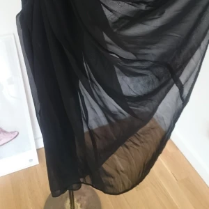  - Helsvart genomskinlig kjol med hög midja i chiffongliknande tyg. Köpt i London, använd enstaka gång. Beroende på hur man vill den ska sitta så funkar den till olika storlekar men storlek som står i är 14/40. Den är ganska liten i storlek, jag har vanligtvis 34-38 i kjolar. Kjolens mått rakt över midja är 36 cm. 