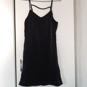  - Kort klänning i glansigt satinmaterial, storlek 36. Aldrig använd. Frakt 20:-