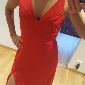  - Röd långklänning med slits vid ena benet.  Använd endast 1 gång på en bankett.  Storlek 34   Finns i Helsingborg och kan skickas mot fraktkostnad. 