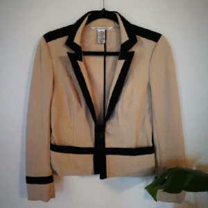  - A classic jacket with a really good fit. It's comfortable and could be worn with a range of things, whether it be more official events or casually with jeans. The color is beige with black detailing.
