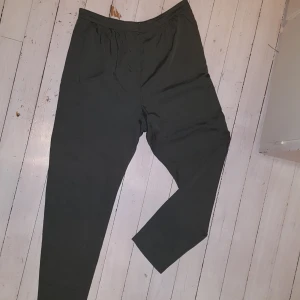  - Tunn bralla i lyocell med fint fall. Grön-grå färg. Fickor 