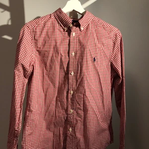 Ralph Lauren skjorta - Ralph Lauren skjorta rutig, använd 1 gång, fin nu till julen (trots mindre firande), fint skick, inga fläckar som ny. Barn storlek, storlek L motsvarande en 13 åring kanske skulle jag tippa på!