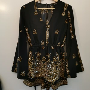 Playsuit - Jättefin svart playsuit med guldigt mönster och guldiga paljetter från Boohoo. Vida ärmar. Storlek 8 UK, (36 EUR). Passar även 34/XS. Använd 1-2 gånger. Nyskick. 