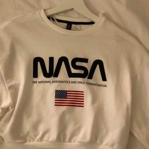 Vit croppad tröja med NASA tryck och svart sträck på armarna. Strl XS. Knappt använd i nyskick. Säljes pga garderobränsning. 50kr+frakt