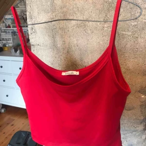  - Ett rött linne av kortare variant (visar lite mage). Använd 1 gång, precis som ny i skick! Köparen står för frakten :)