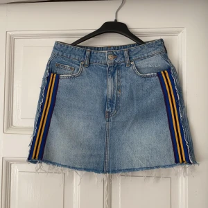 Jeanskjol med färgade streck - Jeanskjol med dragkedja i gylfen och färgade streck vid sidorna