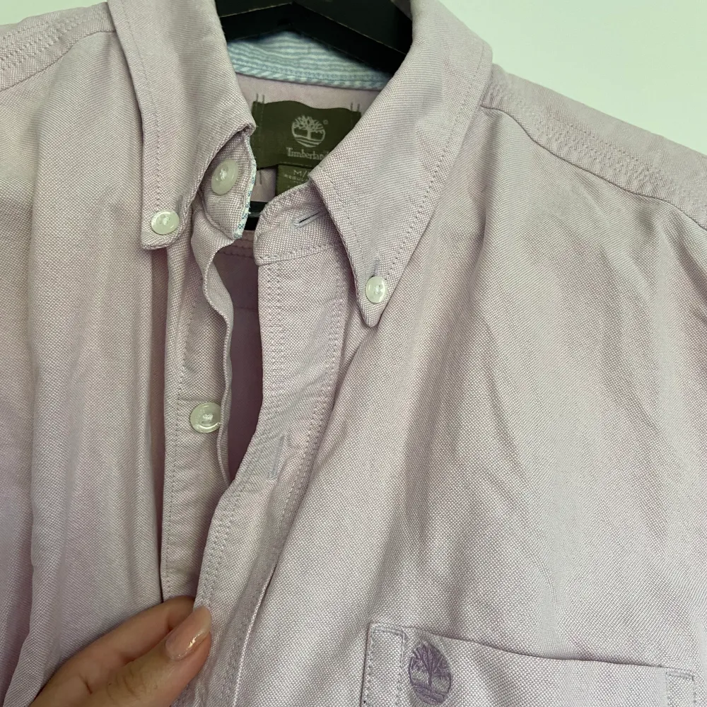 Sååå fin kortärmad skjorta från Timberland i pastellfärg, lila/rosa. Köpt secondhand och i fint skick förutom en liiten missfärgning och ett litet hål från prislappen som jag försökte ta bild på. Syns dock inte om man inte står jättenära tycker jag. 💕. Skjortor.