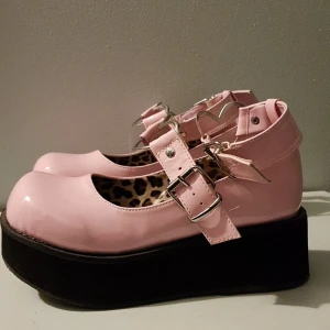 Rosa demonia platåskor - häftiga demonia skor med en 5,5cm lång platå och hjärt spännen. knappt använda, har dock några svarat märken på sidorna. annars i bra skick. säljes för 500kr plus frakt elr upphämtning i kalmar. stl 38,5