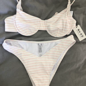 NA-KD bikini, Strl M - Jättefin bikini från NAKD som tyvärr var förstor och är därför helt oanvänd med taggar kvar. Underdelen är en M och toppen är storlek 80B men passar en M. Hur somrig och söt som helst 😍 Köparen står för frakten på 44kr 💕 Nypris: 450kr.
