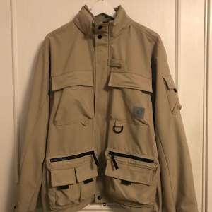 Jacka från carhartt i beige med 11 fickor inkl. Innerficka. Har luva. Skick 8/10. Nypris: 2400kr. Pris kan diskuteras vid snabb affär. DM för fler bilder🤙🏻