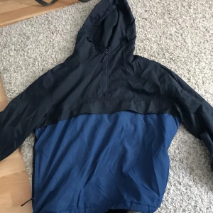 Vindjacka i stl Xl - Vindjacka i bra skick. Lite sliten på vissa ställen o ena ärmen är lite konstig