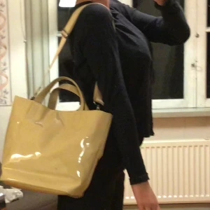 Weekday grocery bag - Skitsnygg och praktisk väska💓 skulle beskriva färgen som sandig, väskan är täckt av något glansigt material. Fläcken som syns på bilderna är borta nu!! 💗 kan användas både som axelväska eller stylish bag, remmen är enkel att ta bort. 