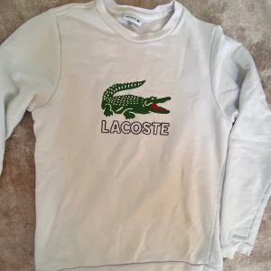 Lacoste tröja Strl 164 (14 år) - Vit Lacoste tröja. Använt skick, svag fläck som inte får bort, se foto