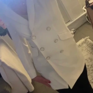 Vit kavaj - En längre kavaj med knappar som går att öppna samt stänga. I fint skick. Strl 36. 