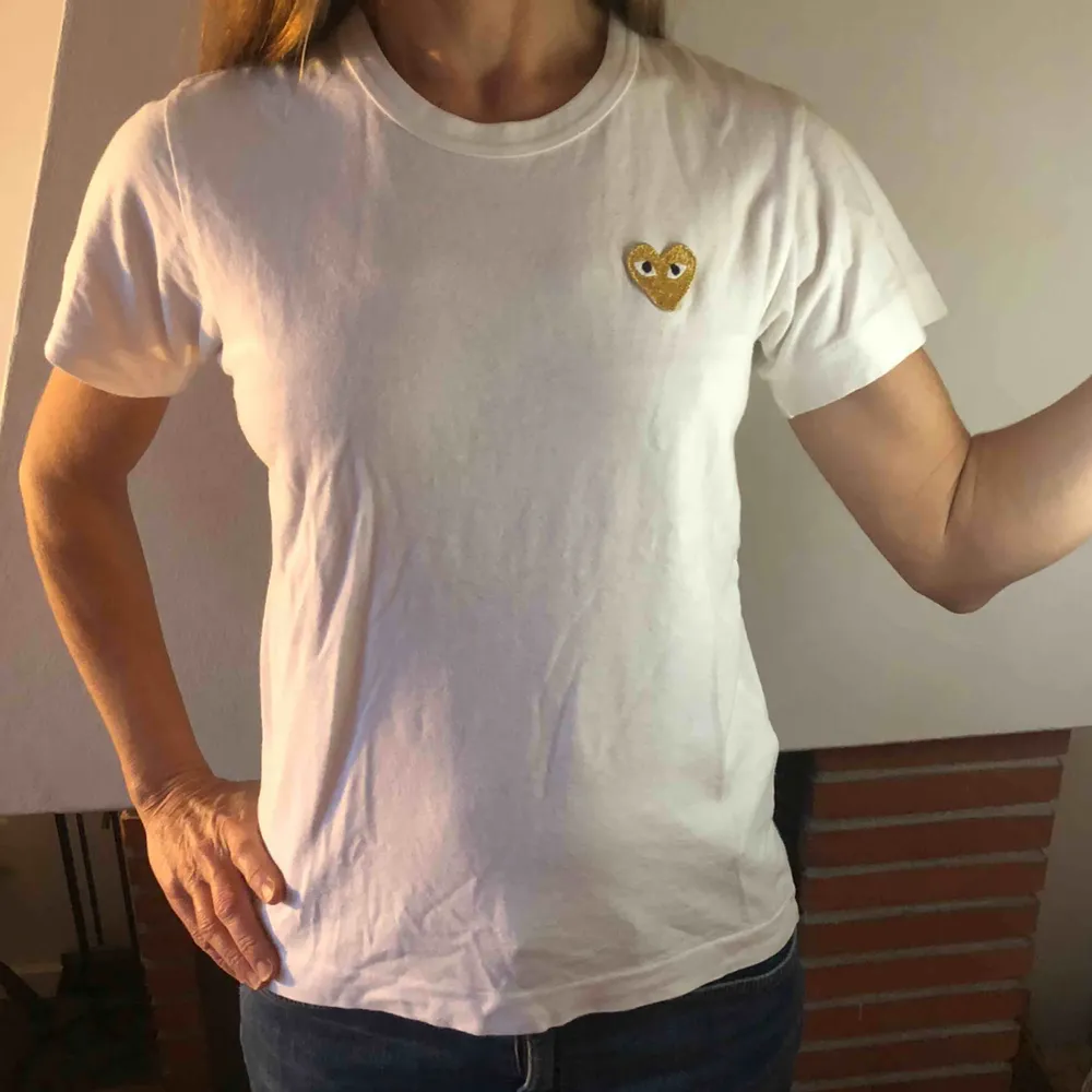 En comme des garçon t-shirt med guldigt hjärta. Använd endast ett fåtal gånger och den är som ny. Köparen står för frakten som ligger på 44kr.. T-shirts.
