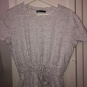 Prickig T-shirt med indragen midja  - Prickig T-shirt med indragen midja och liten rosett fram från zara. Använd 1 gång, storlek m. 