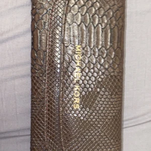 Michael kors plånbok  - En helt ny väldigt fin plånbok. Stor så att massa saker får plats där inne. Brun ormskinn.