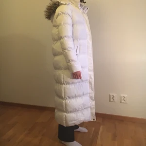 Lång vit puffer jacket  - Lång oanvänd vinterjacka (prislappen är fortfarande kvar). Storlek som passar S och M, Kan passa med xs men då är den oversized. Har två fickor där fram. Har avtagsbar luva. 